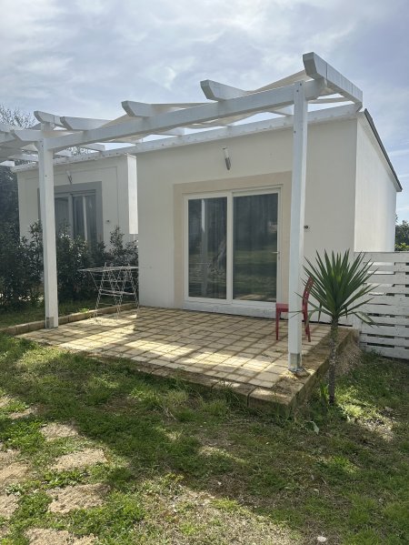 Piccolo edificio bianco con veranda e giardino.