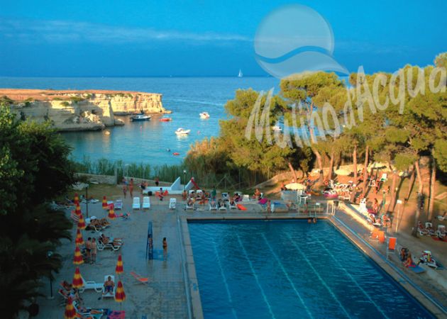 Una piscina all'aperto vicino al mare con ombrelloni e sdraio.