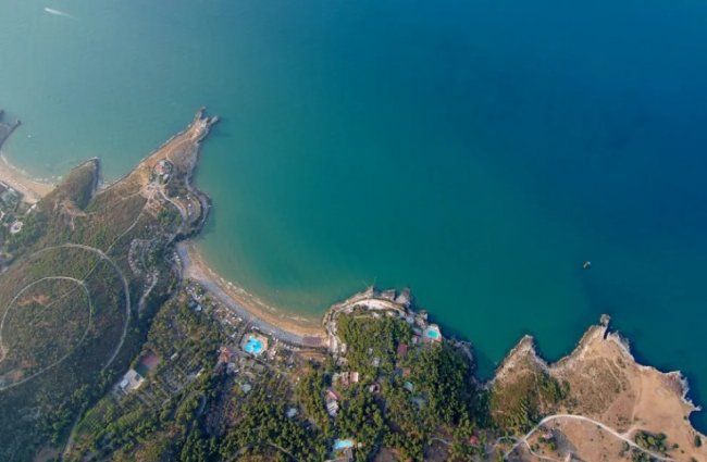 Vista aerea di una baia con mare blu e spiagge.