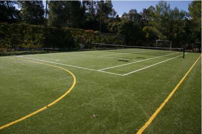 Un campo da tennis in erba sintetica circondato da alberi.