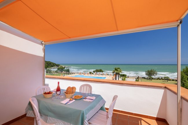 Tavolo all'aperto con vista sul mare e piscina.
