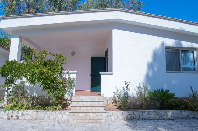 Casa bianca con veranda e piante.