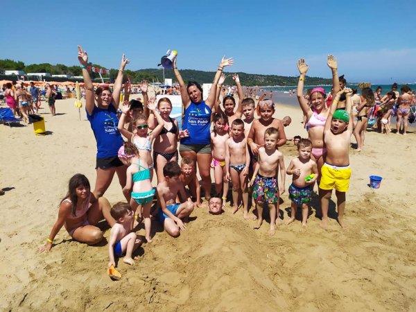 Gruppo di persone sorridenti sulla spiaggia.