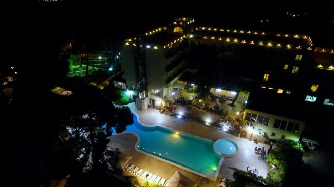 Piscina illuminata di notte accanto a un hotel.