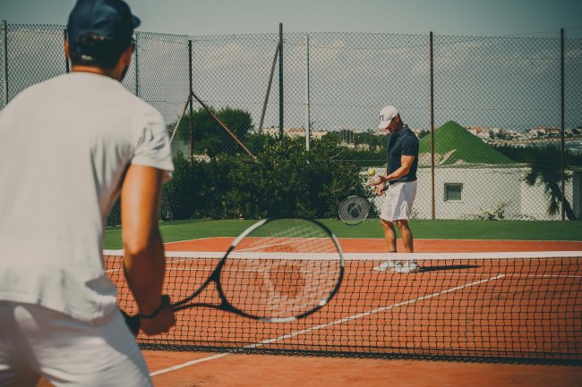 Due persone giocano a tennis su un campo all'aperto.