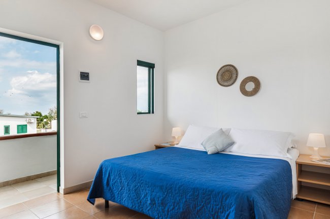 Camera con letto blu e uscita su balcone.