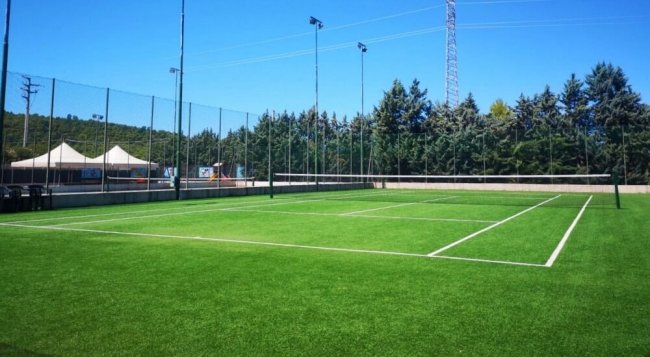 Campo da tennis vuoto con superficie verde.