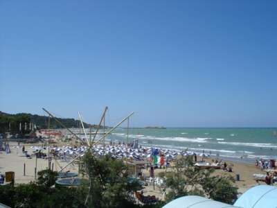 Spiaggia affollata con ombrelloni e mare ondoso.