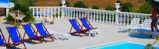 Sdraio blu e lettini bianchi a bordo piscina.