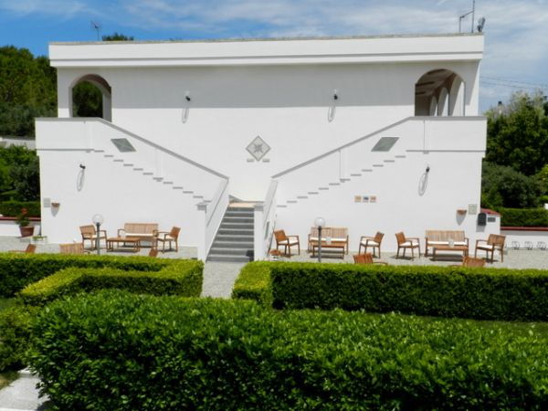 Edificio bianco con due scale simmetriche e panchine.