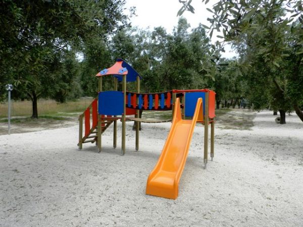 Scivolo arancione nell'area giochi tra gli alberi.
