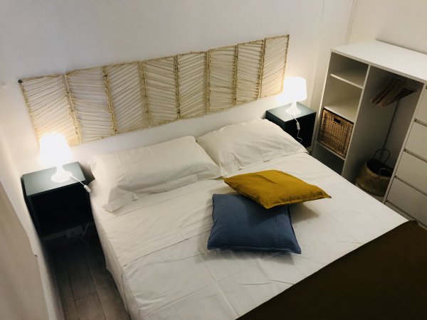 Letto matrimoniale con cuscini colorati e lampade sui comodini.