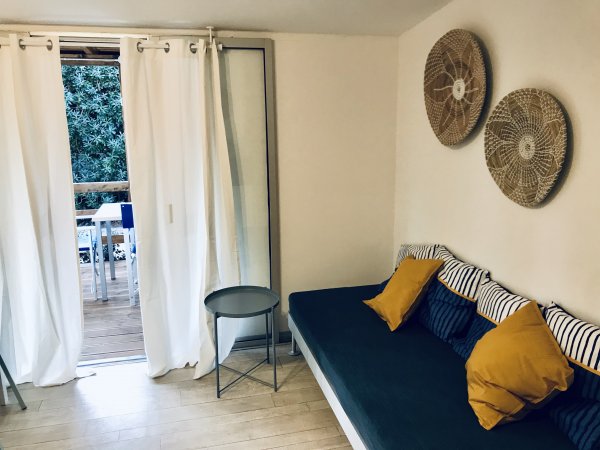 Divano verde con cuscini, tende bianche e balcone.