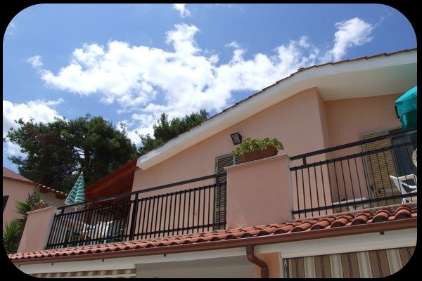 Balcone di casa con tetto spiovente e cielo sereno.