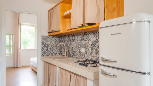 Cucina con piastrelle decorative e frigo retrò.