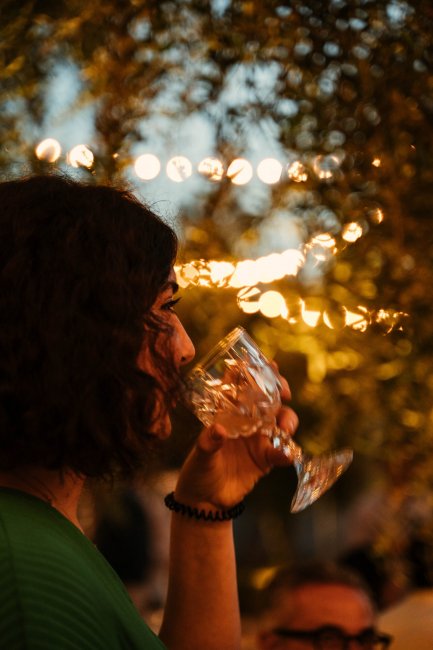 Persona beve vino con luci sullo sfondo.