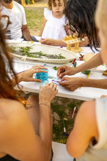 Persone intrecciano fili blu a un tavolo.