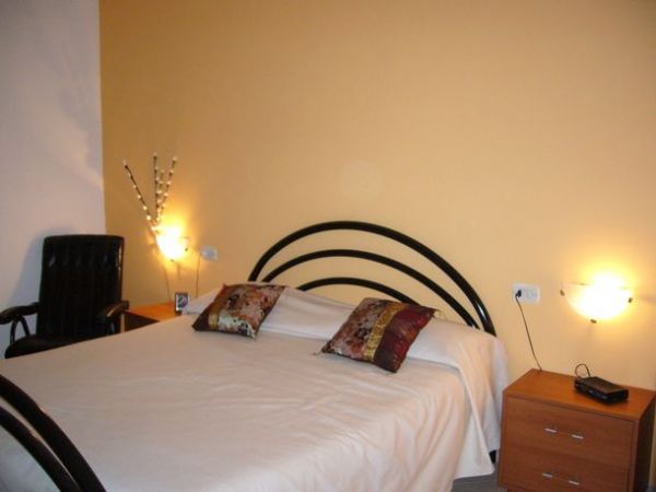 Stanza con letto matrimoniale, cuscini decorativi e comodini.