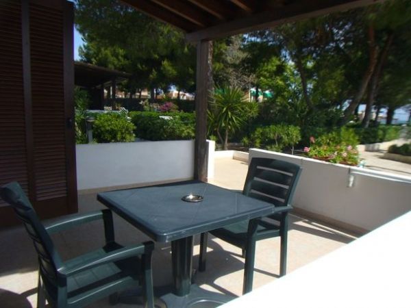 Terrazza con tavolo e sedie di plastica, vista su giardino.