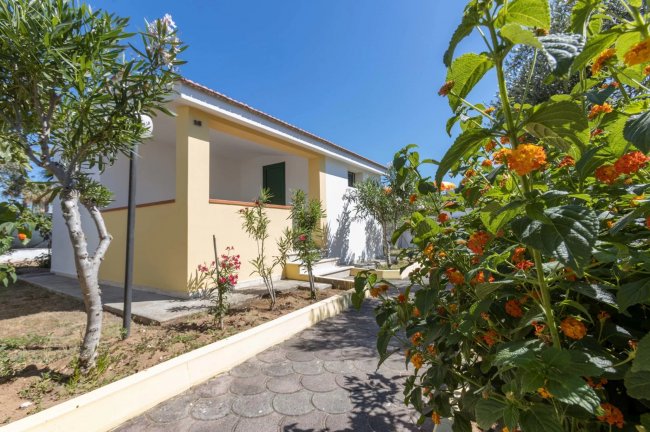 Edificio giallo con giardino fiorito e vialetto.