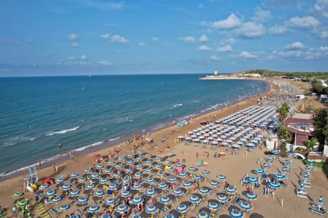 Spiaggia affollata con ombrelloni blu.