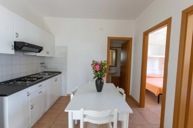 Cucina bianca con tavolo e fiori.
