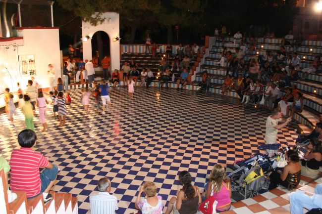 Spettacolo serale all'aperto con bambini e pubblico in anfiteatro.