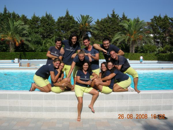 Gruppo sorridente davanti a una piscina con alberi.