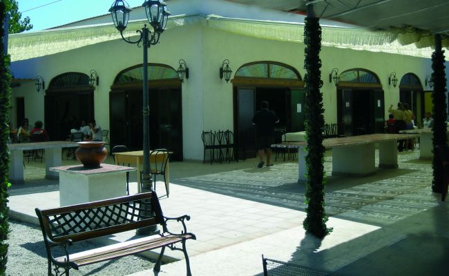 Cortile esterno di un edificio con panchine e tavoli.