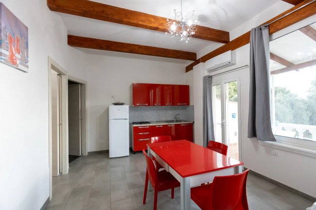 Cucina moderna con tavolo rosso e sedie abbinate.