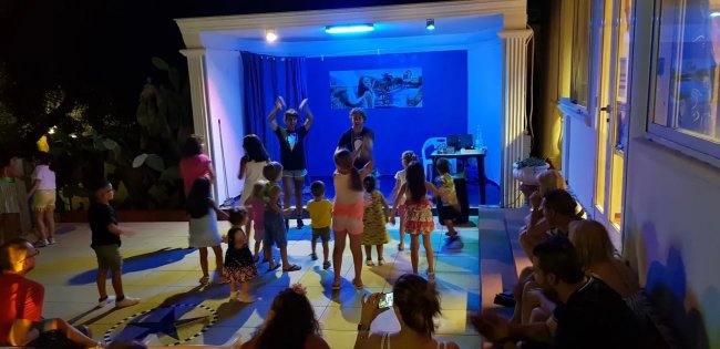Un gruppo di bambini balla su un palco all'aperto.
