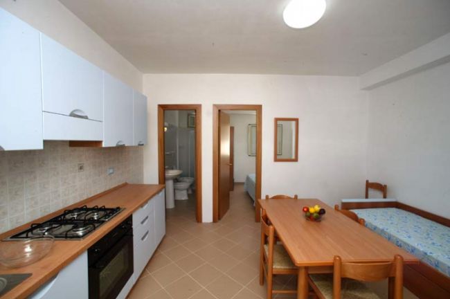 Cucina-soggiorno con tavolo da pranzo e fornelli.