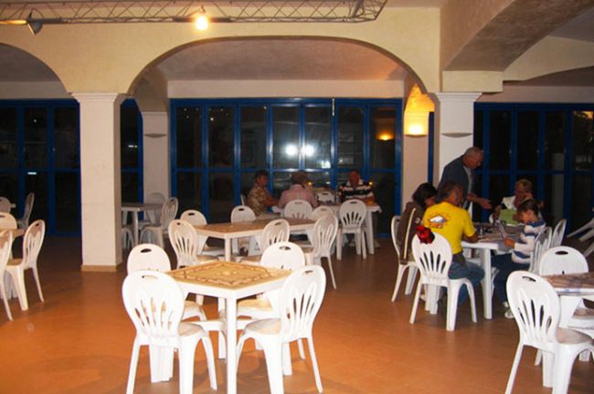 Ristorante con sedie bianche e tavoli occupati.