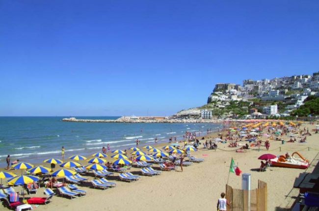Spiaggia affollata con ombrelloni gialli e blu.