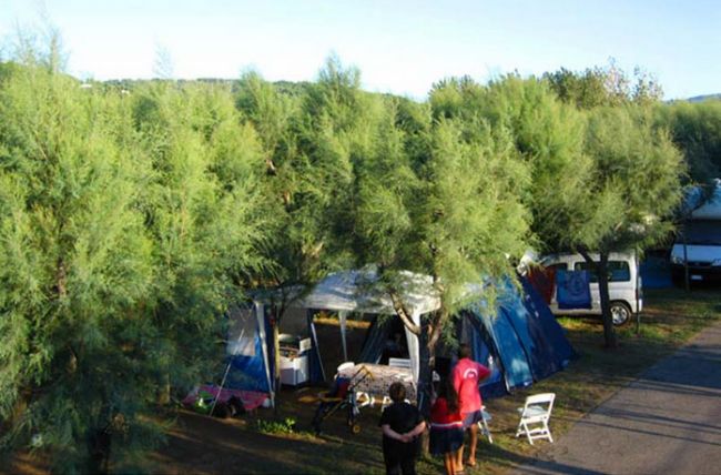 Tenda blu e verde tra alberi, persone in piedi.
